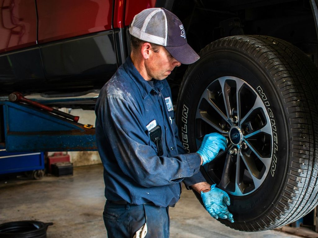 how far can you drive on a spare tire - mechanic mounting a wheel
