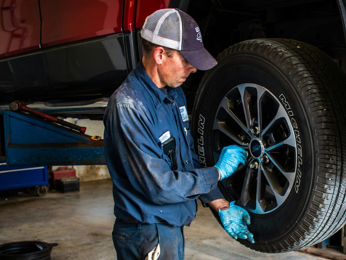 how far can you drive on a spare tire - mechanic mounting a wheel